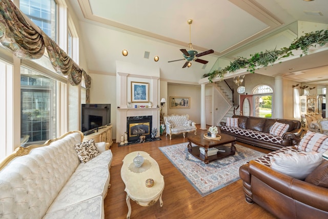 living room with ornate columns, a fireplace, stairway, and wood finished floors