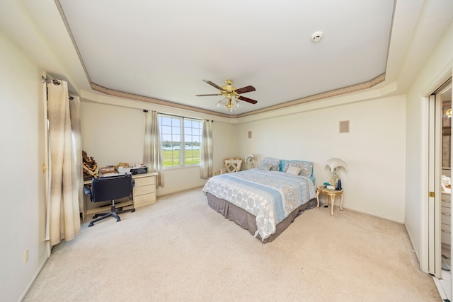 bedroom with ceiling fan, a tray ceiling, and light colored carpet