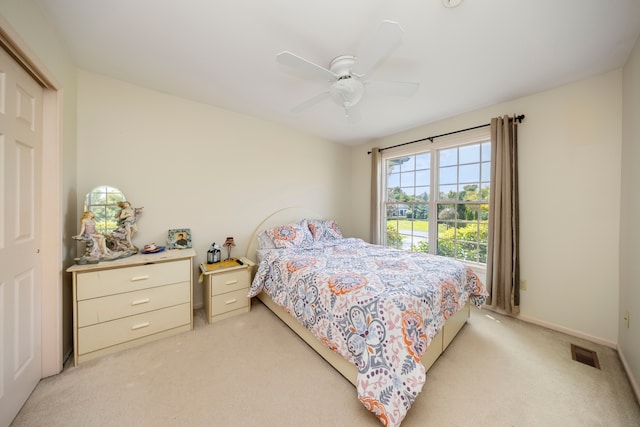 bedroom with baseboards, a ceiling fan, visible vents, and light colored carpet