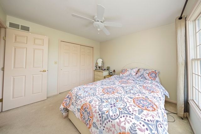 bedroom with light carpet, visible vents, baseboards, a ceiling fan, and a closet