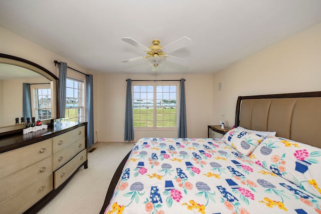 bedroom featuring light carpet, ceiling fan, and multiple windows