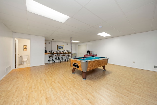 recreation room with visible vents, a bar, a drop ceiling, and light wood-style flooring