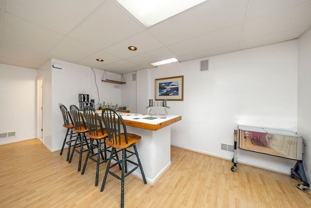 bar featuring a paneled ceiling, wood finished floors, visible vents, baseboards, and a dry bar