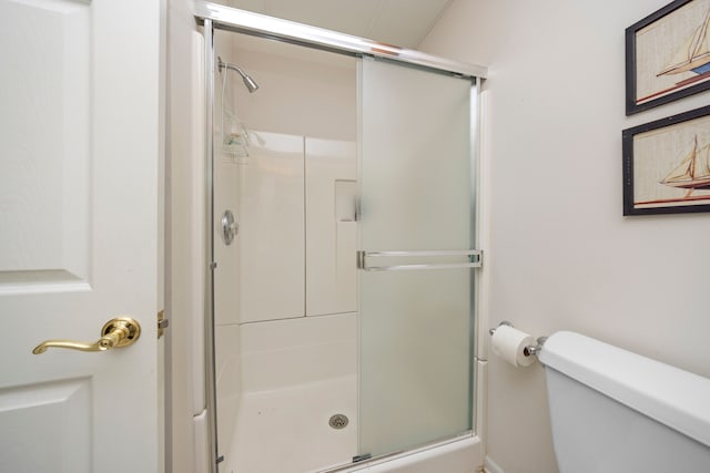 bathroom featuring toilet and a shower stall