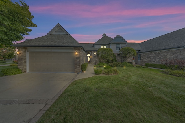 view of front of home featuring a garage, concrete driveway, brick siding, and a yard