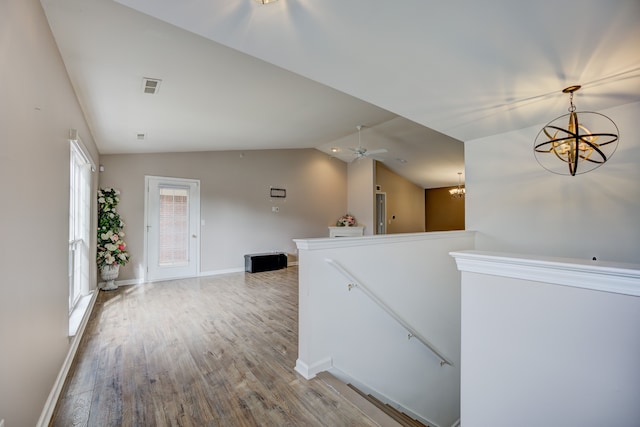 hallway with light wood finished floors, baseboards, an inviting chandelier, vaulted ceiling, and an upstairs landing