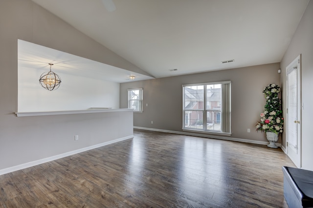 unfurnished living room featuring dark wood-style floors, a chandelier, visible vents, and baseboards