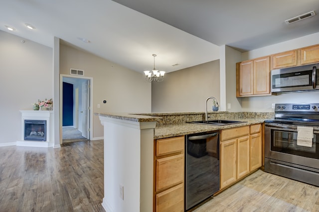 kitchen featuring light brown cabinetry, a peninsula, appliances with stainless steel finishes, and visible vents