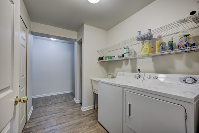 clothes washing area with laundry area, light wood-style flooring, baseboards, and separate washer and dryer