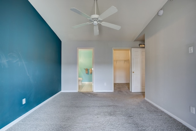 unfurnished bedroom with carpet floors, baseboards, vaulted ceiling, a spacious closet, and a closet