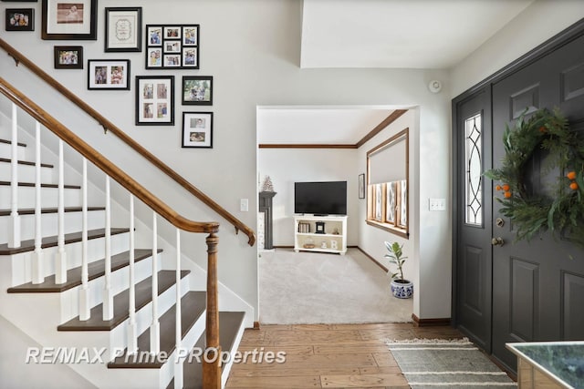 foyer entrance with stairs, wood finished floors, and baseboards