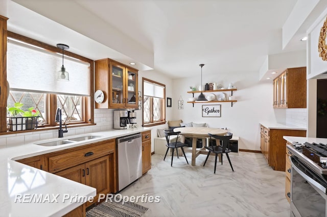 kitchen with appliances with stainless steel finishes, brown cabinetry, a sink, and tasteful backsplash