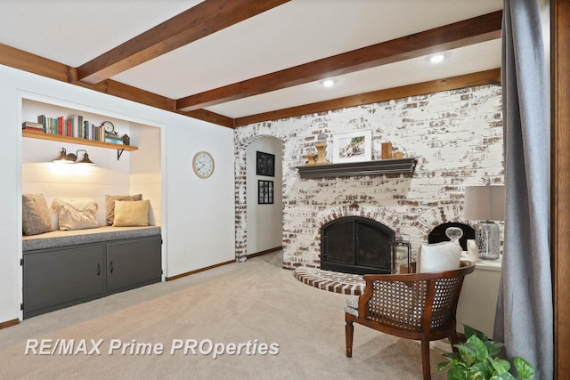 living room with baseboards, arched walkways, light colored carpet, beamed ceiling, and a brick fireplace