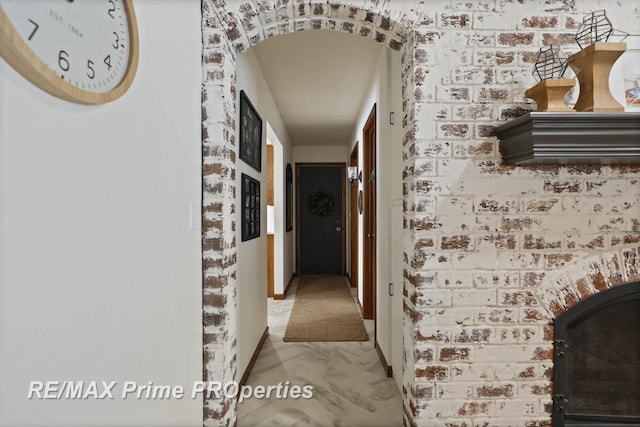 hall featuring brick wall and arched walkways