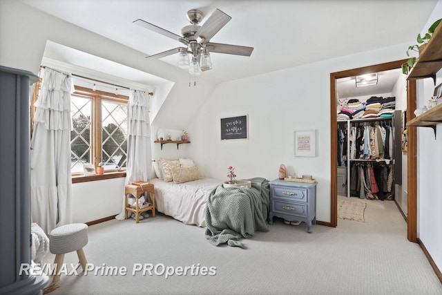 bedroom featuring a walk in closet, carpet, a closet, a ceiling fan, and baseboards