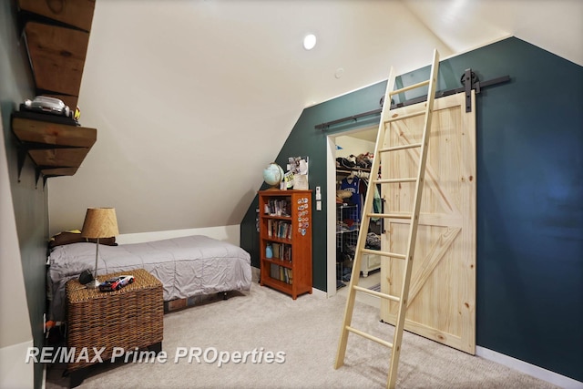 bedroom featuring lofted ceiling, carpet floors, a barn door, and baseboards