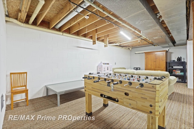 rec room with concrete block wall and light colored carpet