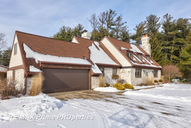 view of front of house featuring a garage, stone siding, and a chimney