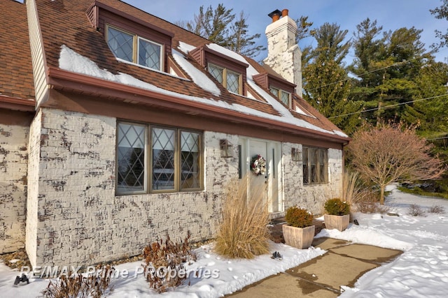 view of front of property featuring a chimney and roof with shingles