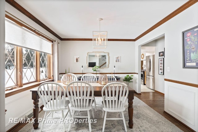 dining room with a notable chandelier, baseboards, wood finished floors, and crown molding