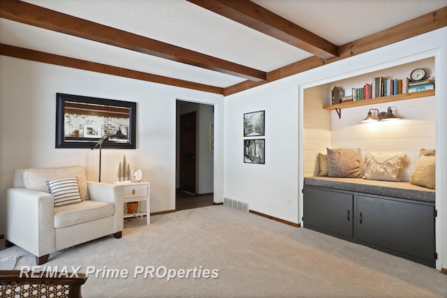 living area featuring visible vents, light carpet, a textured ceiling, beamed ceiling, and baseboards