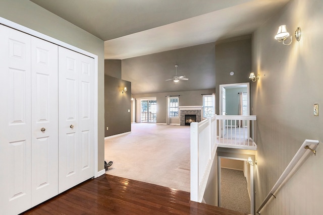 hallway with an upstairs landing, wood finished floors, carpet flooring, baseboards, and vaulted ceiling