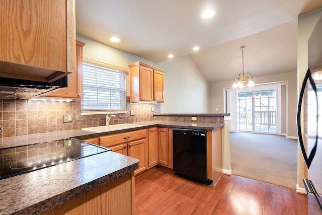 kitchen featuring tasteful backsplash, vaulted ceiling, a peninsula, black appliances, and a sink