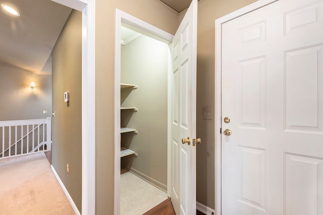 hall with an upstairs landing, carpet, and baseboards