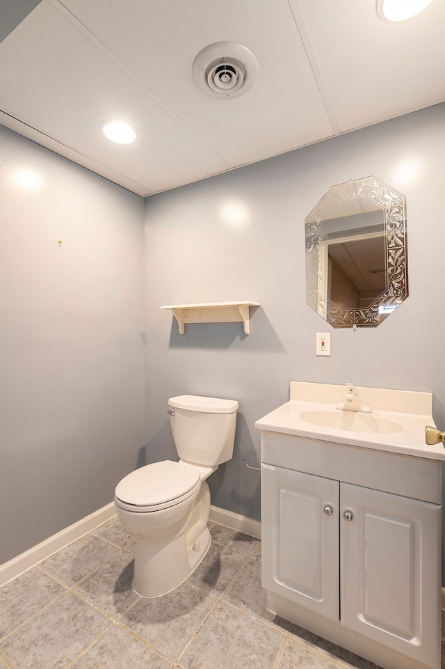 half bath with vanity, toilet, visible vents, and baseboards