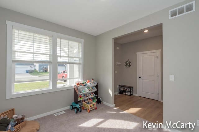 recreation room featuring carpet floors, visible vents, and baseboards