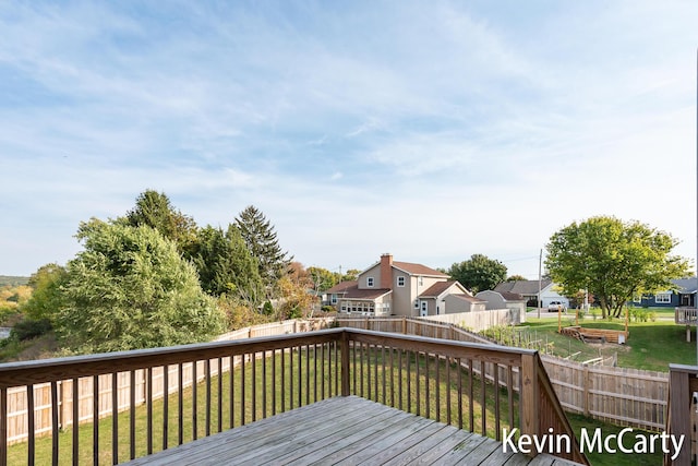 wooden terrace with a residential view, a fenced backyard, and a yard