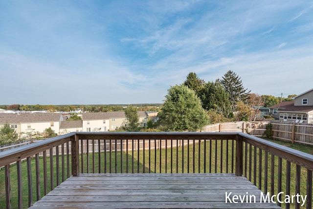 wooden terrace featuring a residential view, a fenced backyard, and a lawn