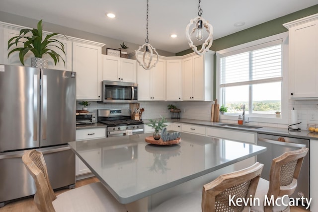 kitchen with appliances with stainless steel finishes, a breakfast bar area, a sink, and white cabinetry