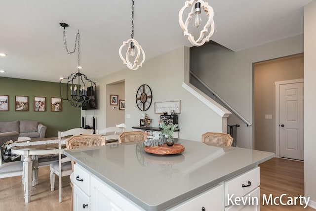 kitchen featuring open floor plan, light wood-style flooring, white cabinetry, and pendant lighting