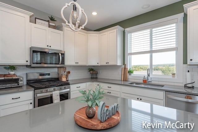 kitchen featuring a toaster, decorative backsplash, appliances with stainless steel finishes, white cabinetry, and a sink