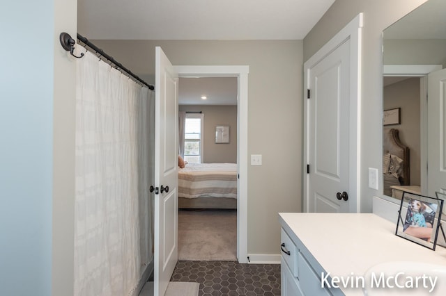 ensuite bathroom featuring a shower with shower curtain, baseboards, connected bathroom, and vanity