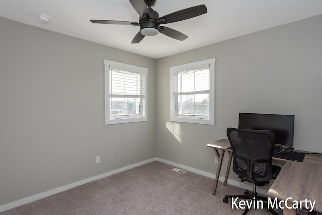 unfurnished office featuring carpet floors, visible vents, baseboards, and a ceiling fan