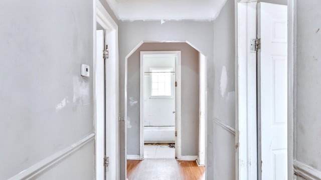 hall featuring arched walkways and light wood finished floors