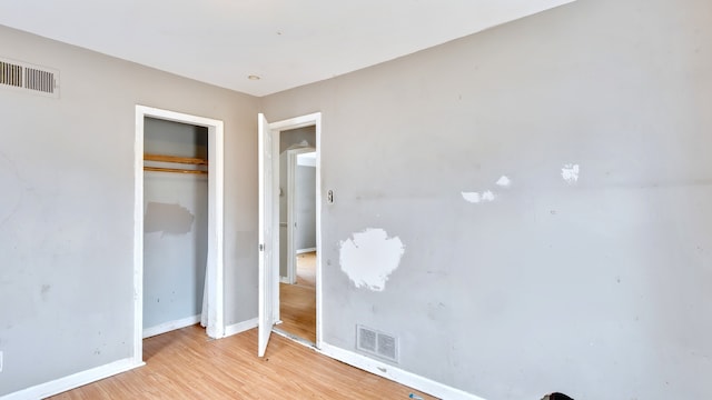 unfurnished bedroom featuring a closet, light wood-type flooring, visible vents, and baseboards