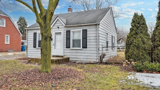 bungalow-style home with a shingled roof, fence, and a chimney