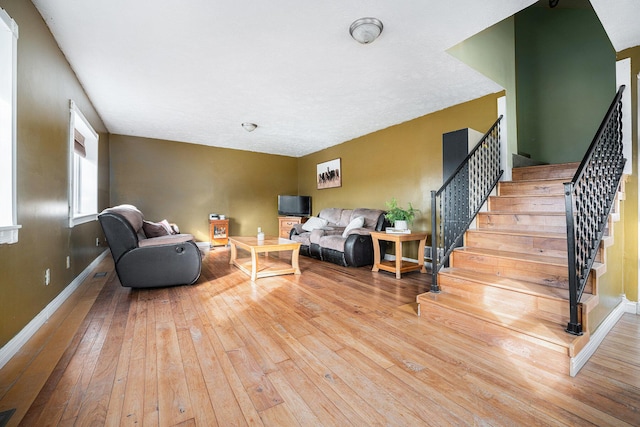 living area with stairway, baseboards, and hardwood / wood-style flooring