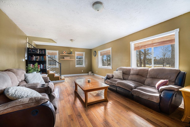 living area featuring wood-type flooring, a textured ceiling, baseboards, and stairs