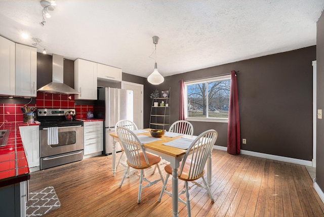 dining space featuring a textured ceiling, light wood-style flooring, and baseboards