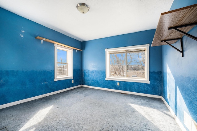 carpeted empty room featuring baseboards