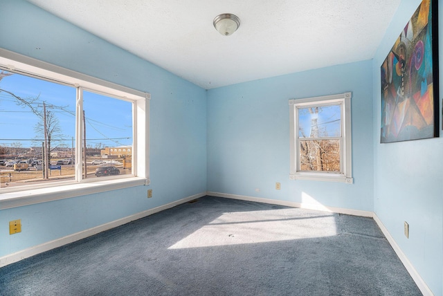 carpeted empty room featuring a textured ceiling and baseboards