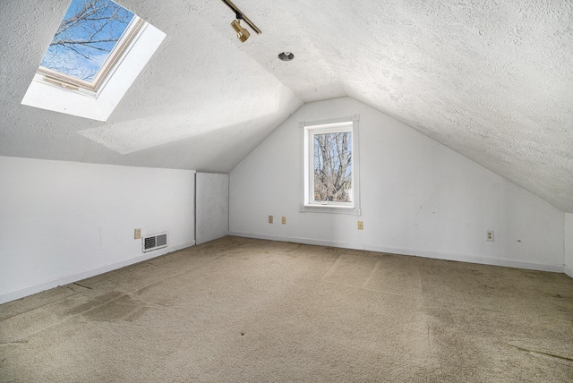 additional living space with carpet floors, baseboards, visible vents, and lofted ceiling with skylight