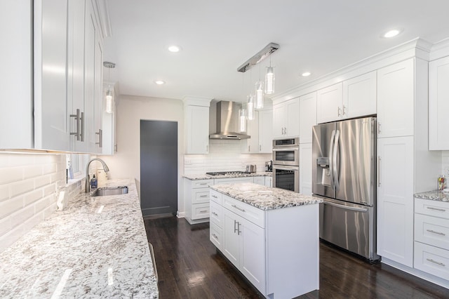 kitchen with dark wood-style floors, wall chimney exhaust hood, appliances with stainless steel finishes, white cabinetry, and a sink