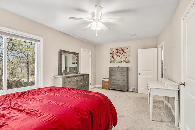 bedroom featuring light colored carpet, ceiling fan, visible vents, and baseboards