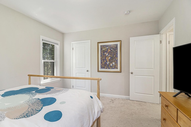 bedroom featuring light carpet and baseboards