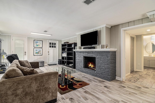 living room with a fireplace, wood finished floors, visible vents, and baseboards